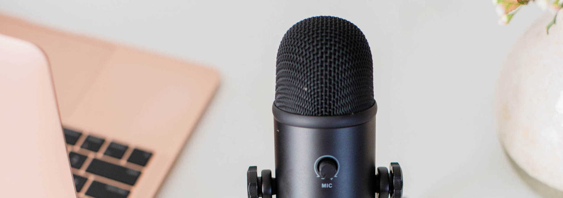 A microphone sitting on a desk next to a laptop.
